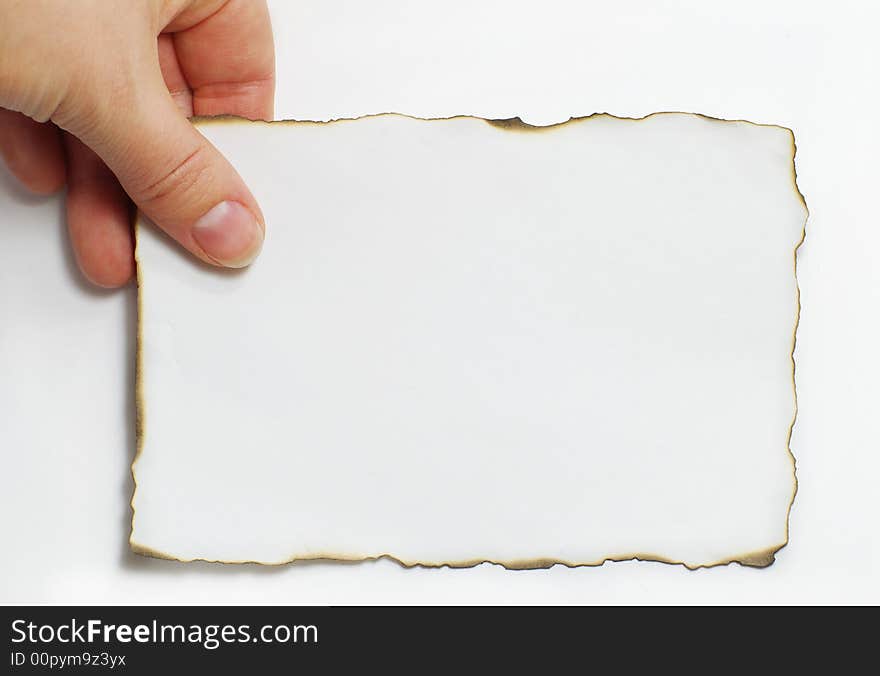 The hand holds a burnt leaf of a paper