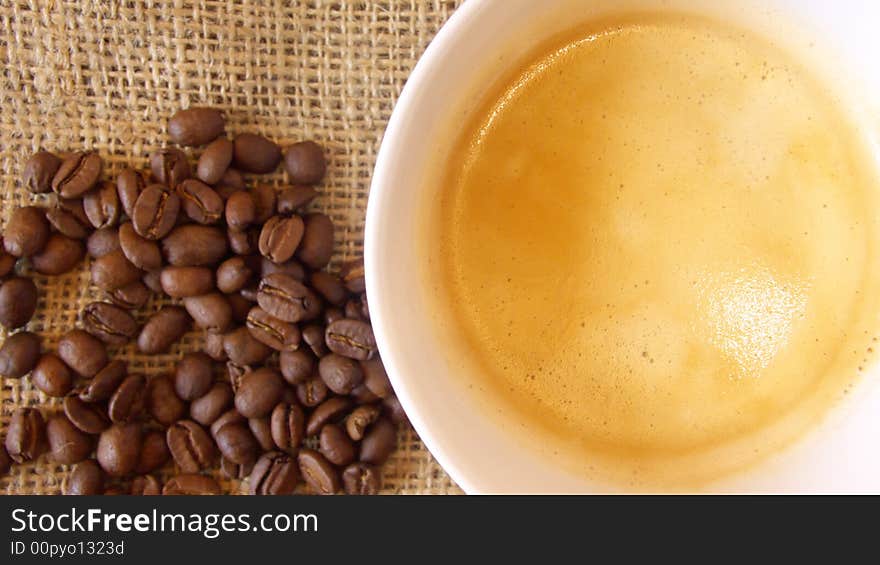 Cup of coffee with cream arranged with linen and coffee beans. Cup of coffee with cream arranged with linen and coffee beans