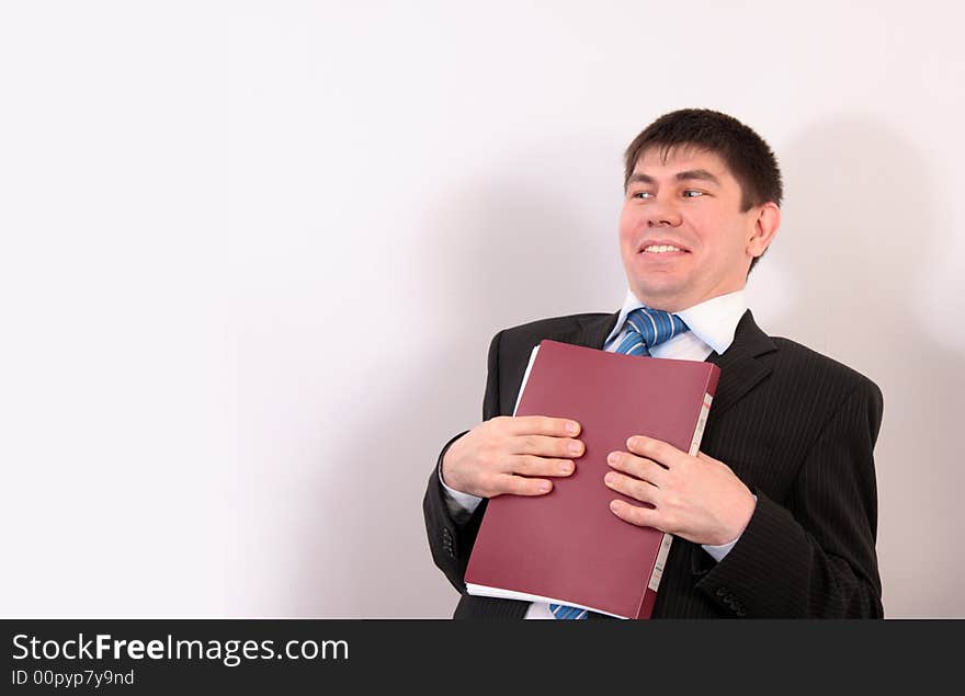 Man in a suit presses a folder with papers to a breast and smiles. Man in a suit presses a folder with papers to a breast and smiles.