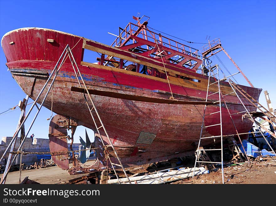 Morocco, Essaouira:repairing a  red and old fishing boat. Morocco, Essaouira:repairing a  red and old fishing boat