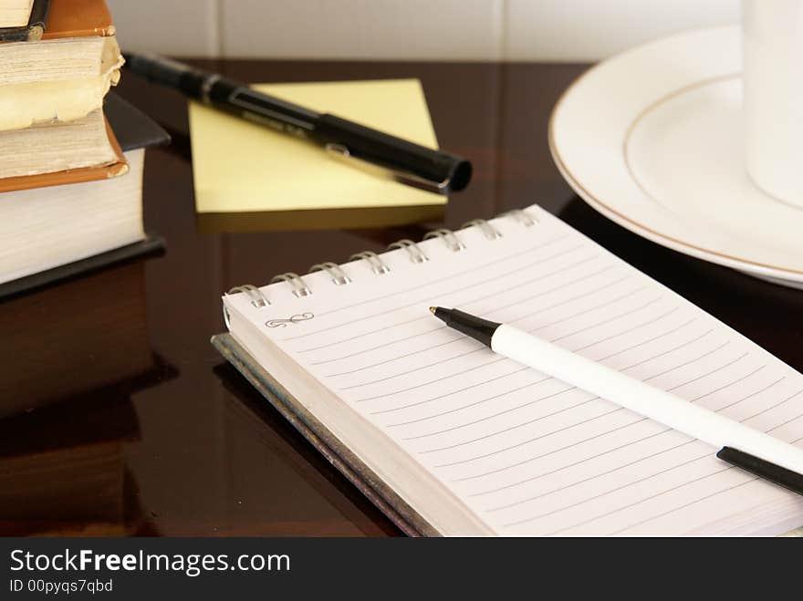 Office desk with notepads, pens, coffee and doughnuts. Office desk with notepads, pens, coffee and doughnuts