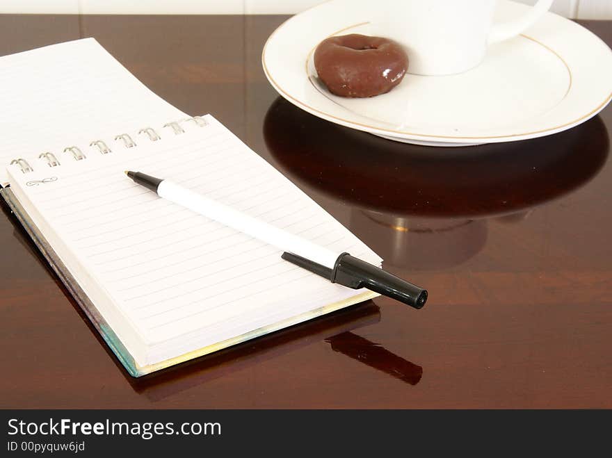 Office desk with notepads, pens, coffee and doughnuts. Office desk with notepads, pens, coffee and doughnuts