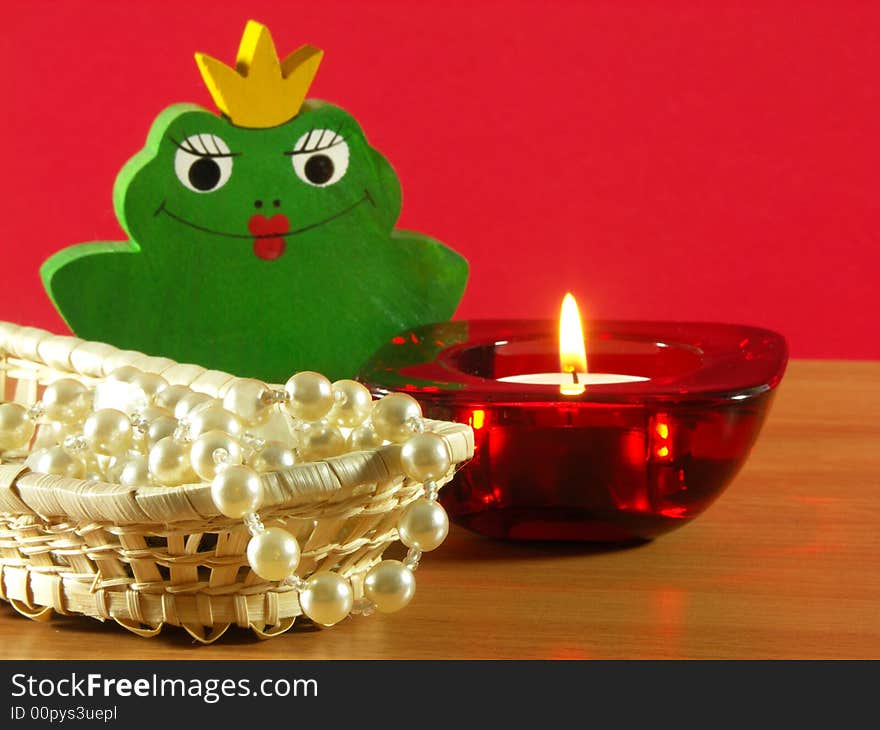 The candle and pearls on the table. Red background. The candle and pearls on the table. Red background.