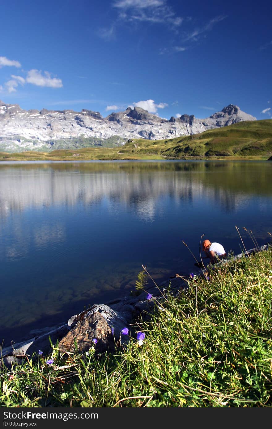 Alps in the reflection of the lakeTannensee. People visible on the board of the lake. Alps in the reflection of the lakeTannensee. People visible on the board of the lake.