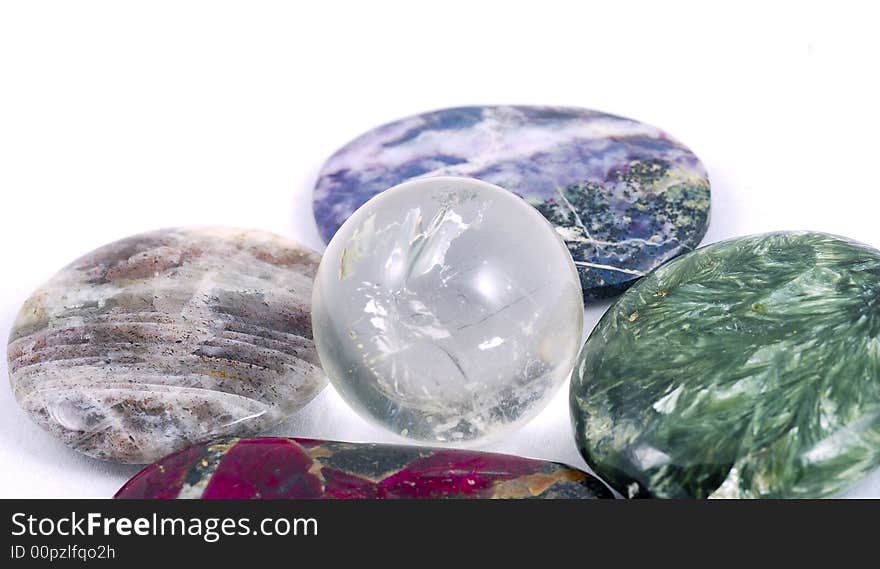 A structured crystal sphere surrounded with colored stones as an egg in a nest, on white. A structured crystal sphere surrounded with colored stones as an egg in a nest, on white