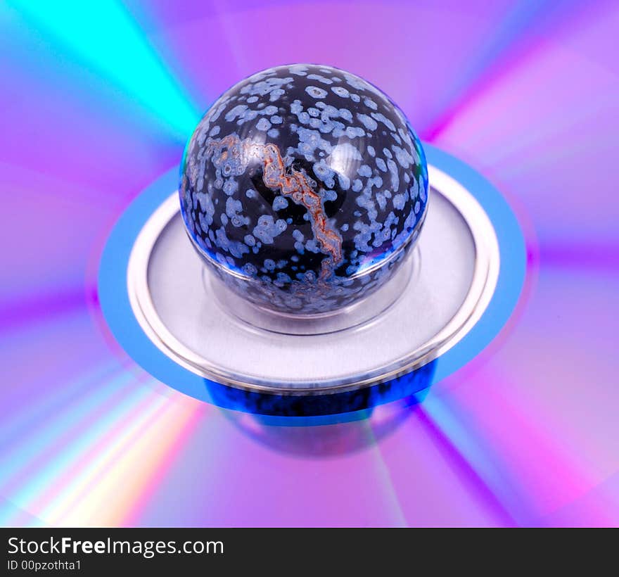 Small painted stone ball on a compact disk surface with a rainbow effect. Small painted stone ball on a compact disk surface with a rainbow effect