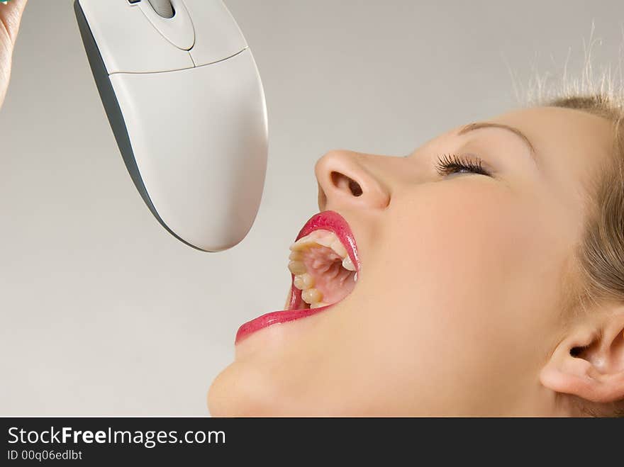 Pretty young caucasian girl pretending to eating computer mouse. Pretty young caucasian girl pretending to eating computer mouse