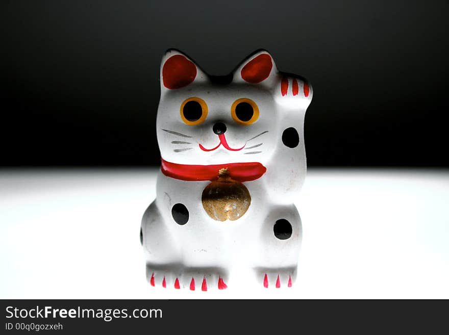 Asian good luck cat (Maneki Neko) which is believed to bring good luck and money.(on a black and white background). Asian good luck cat (Maneki Neko) which is believed to bring good luck and money.(on a black and white background)