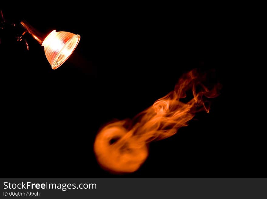 The smoke from a cigarette flies under a lamp. The smoke from a cigarette flies under a lamp