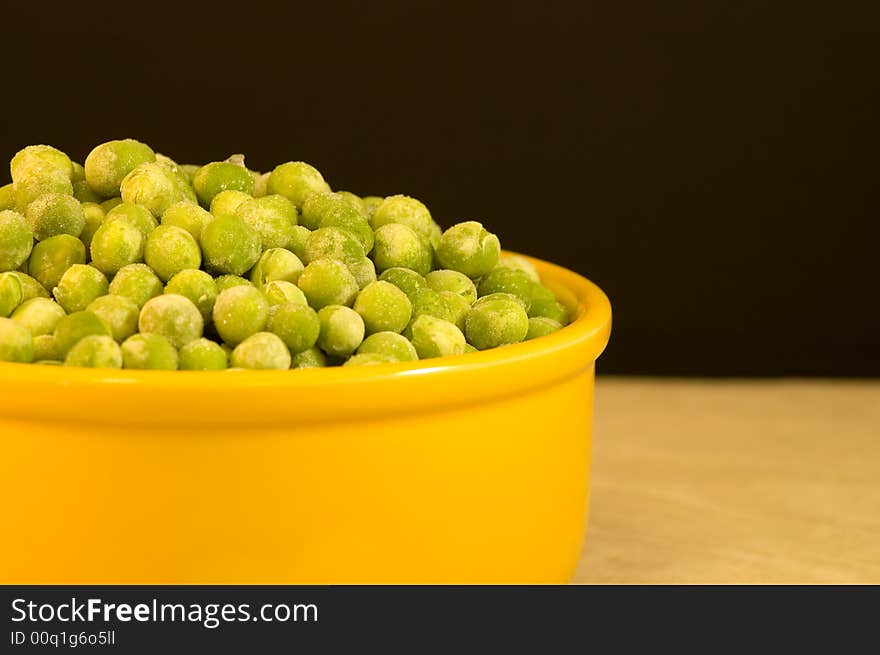 A closeup view of a yellow bowl of 
frozen green peas ready to be cooked and eaten. A closeup view of a yellow bowl of 
frozen green peas ready to be cooked and eaten.