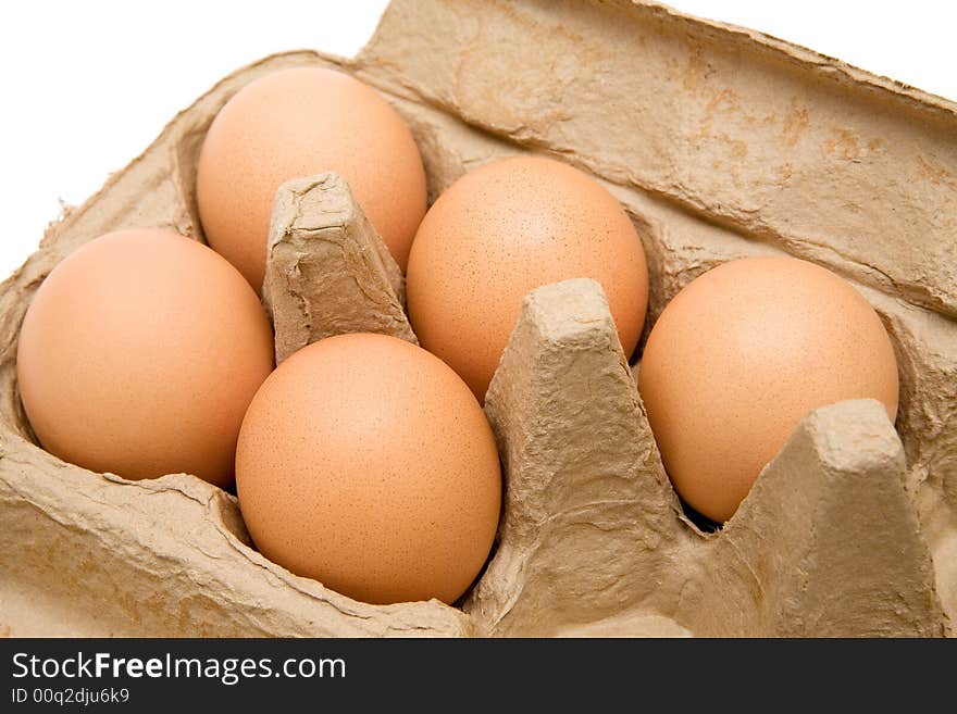 Five brown eggs in a carton. White background.