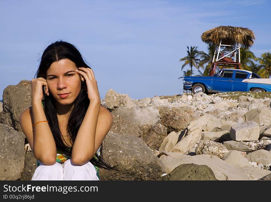 Girl Sitting On Rocky Beach