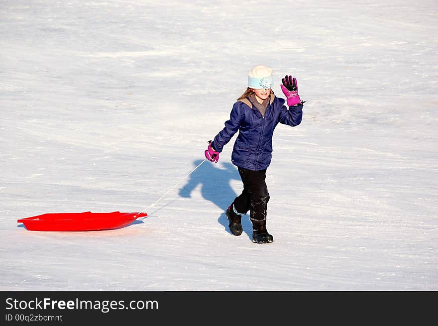 One little girl sledding on a winter day in a red sled