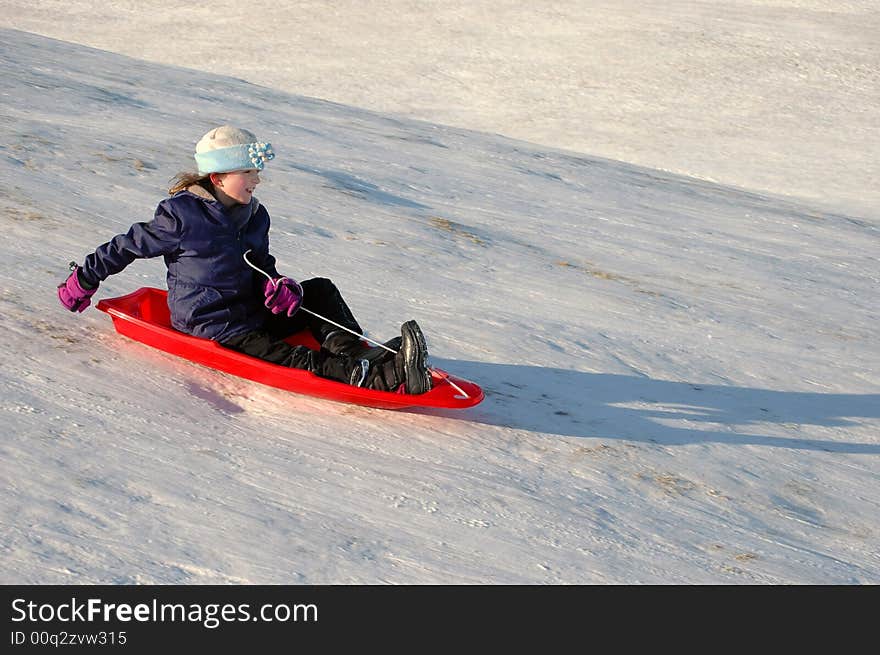 One little girl sledding on a winter day in a red sled