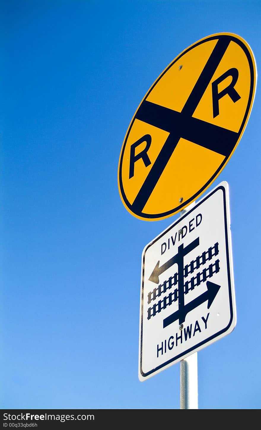 A sign indicating that there is a railroad crossing and a divided highway. A sign indicating that there is a railroad crossing and a divided highway.