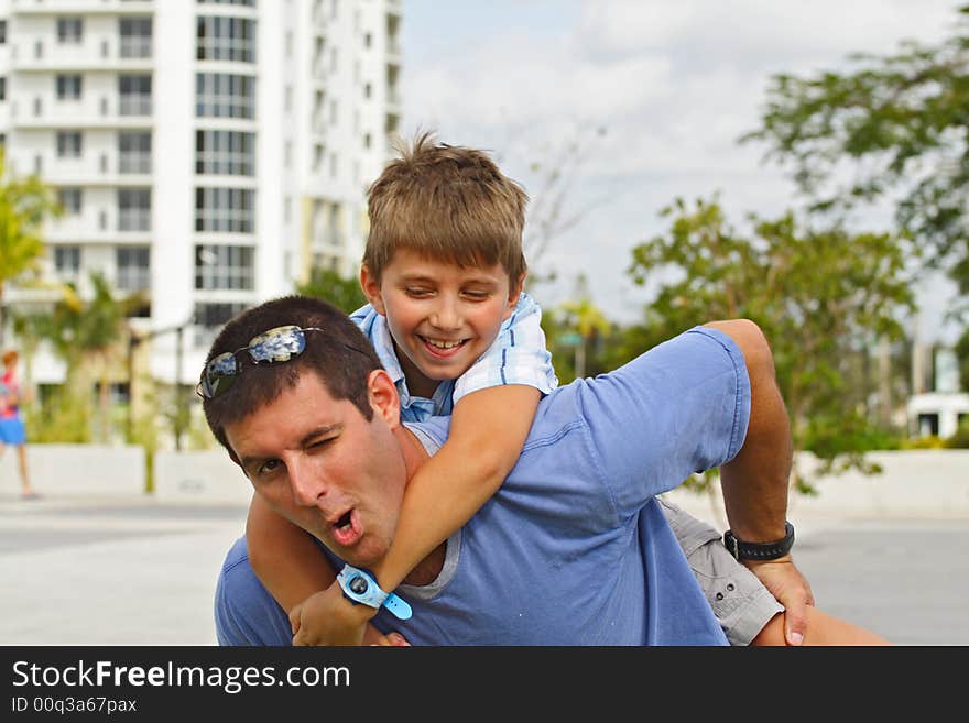 Boy Holding on to a guy. Both Smiling and making funny faces