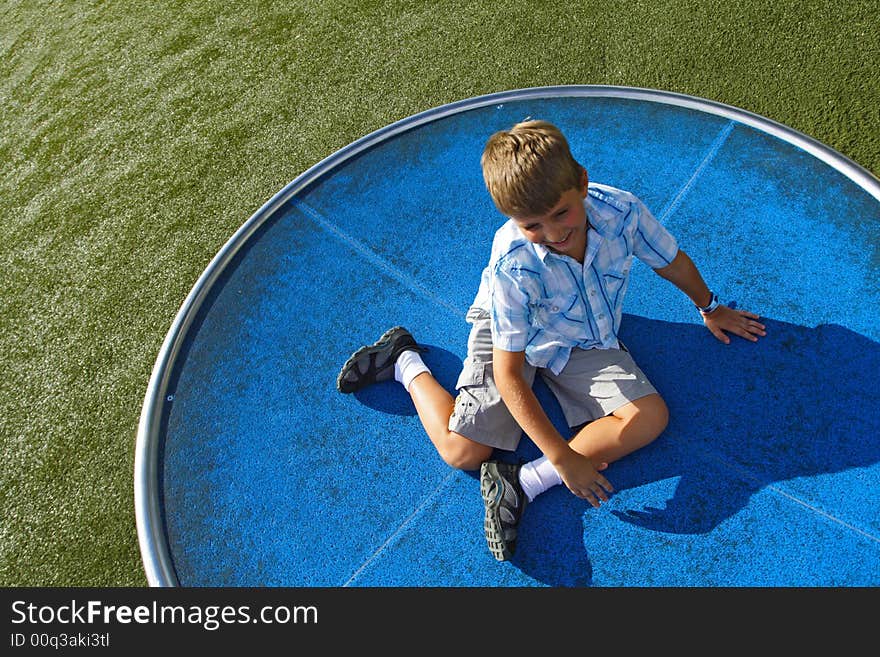 Boy spinning on a turn table in the park. Boy spinning on a turn table in the park