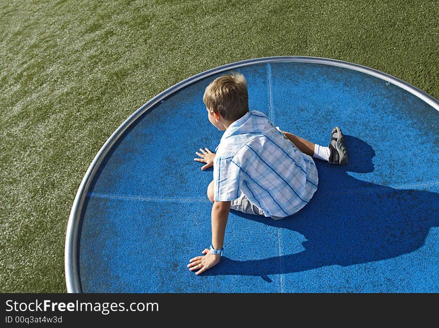 Boy spinning on a turn table in the park. Boy spinning on a turn table in the park