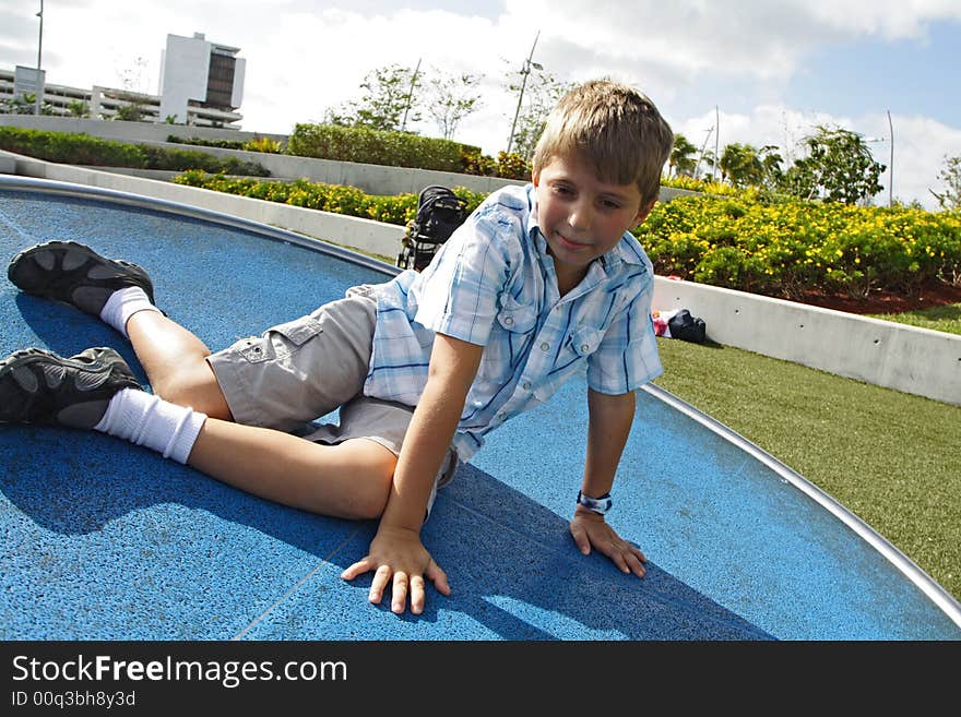 Boy spinning on a turn table in the park. Boy spinning on a turn table in the park