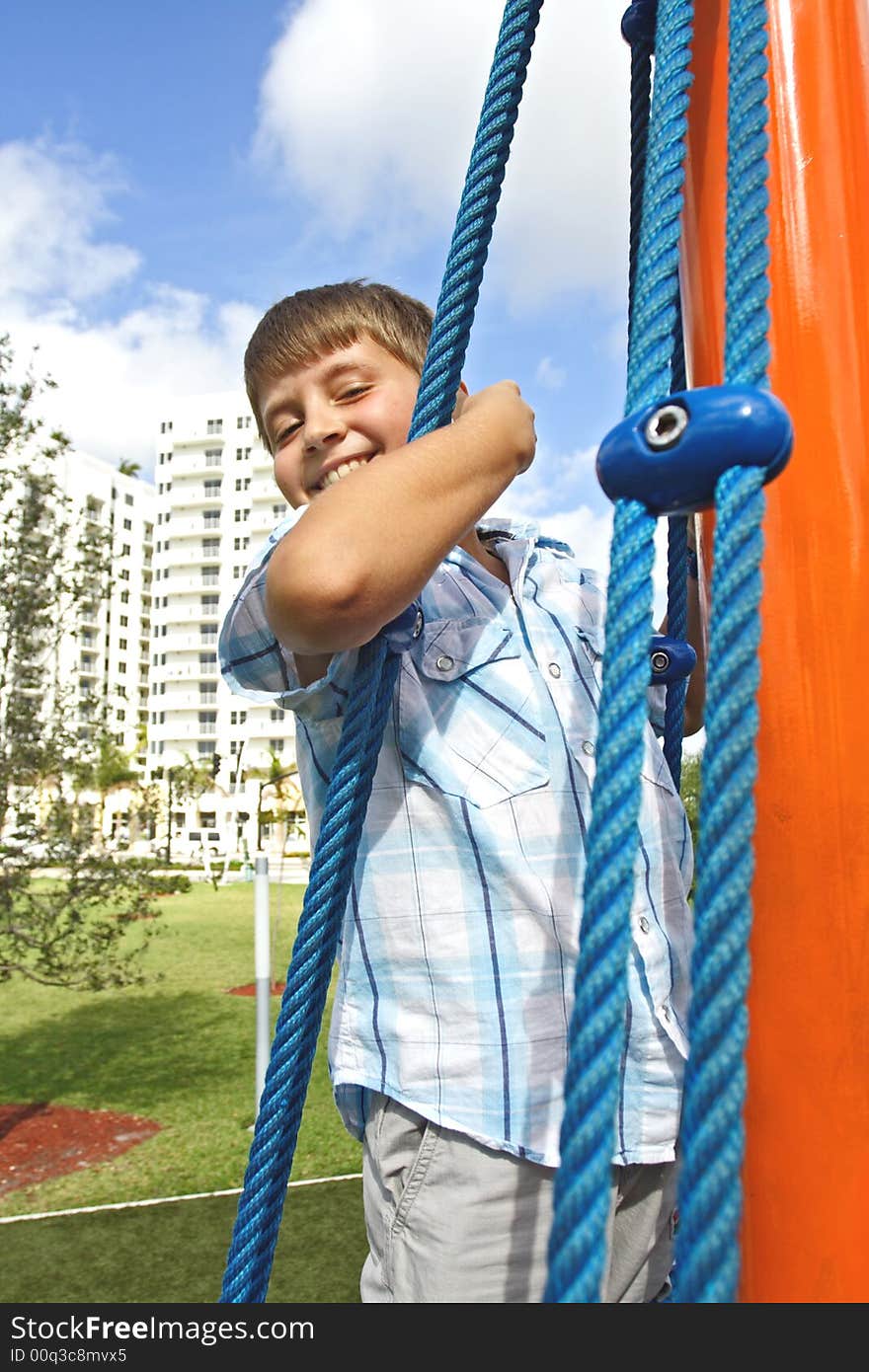 Kid holding on to blue ropes and smiling. Kid holding on to blue ropes and smiling