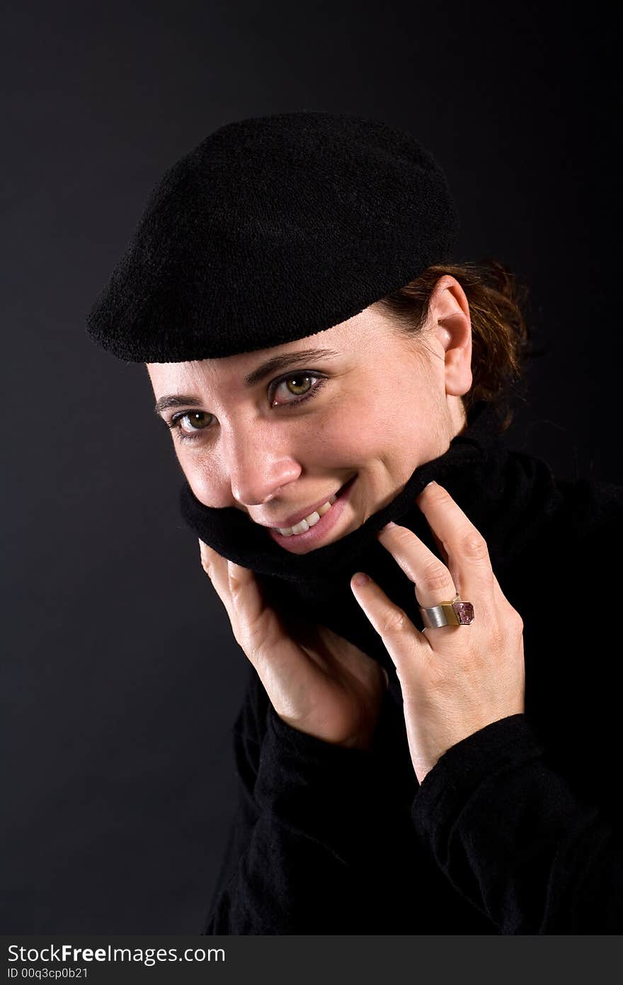 Nice smiling woman with black Pullover and black hat on dark background. Nice smiling woman with black Pullover and black hat on dark background.