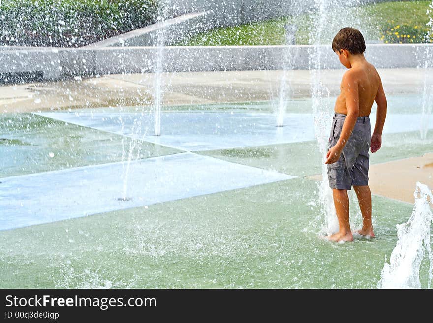 Boy playing in the water fountains. Boy playing in the water fountains