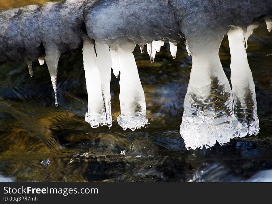 Artistic icicles hanging over a creek. Artistic icicles hanging over a creek.