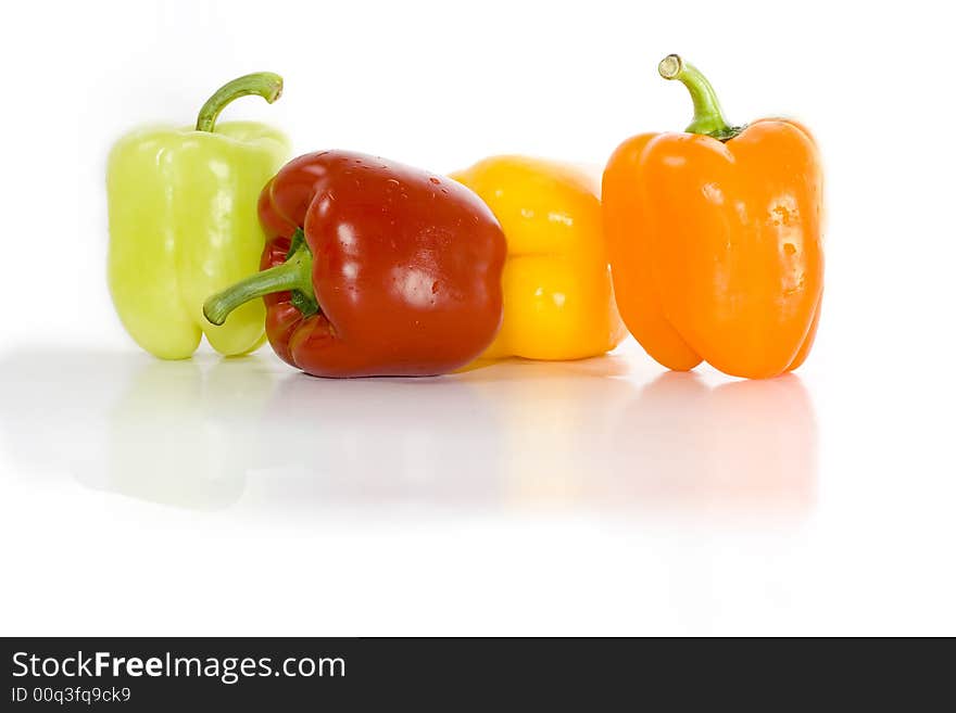 Four colored peppers isolated on white with reflection on glossy surface.