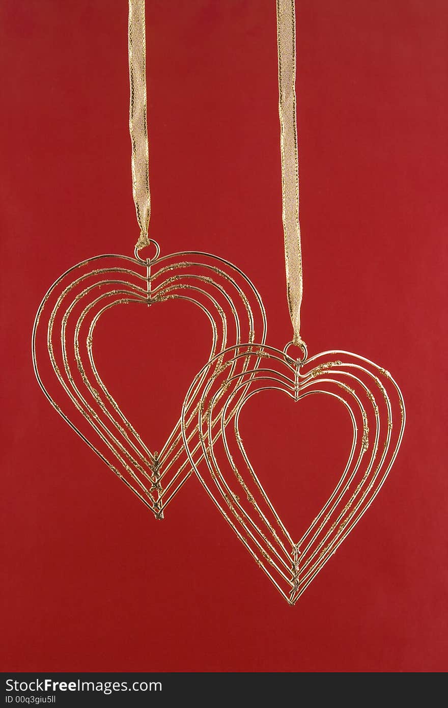 Two gold hearts on a red background