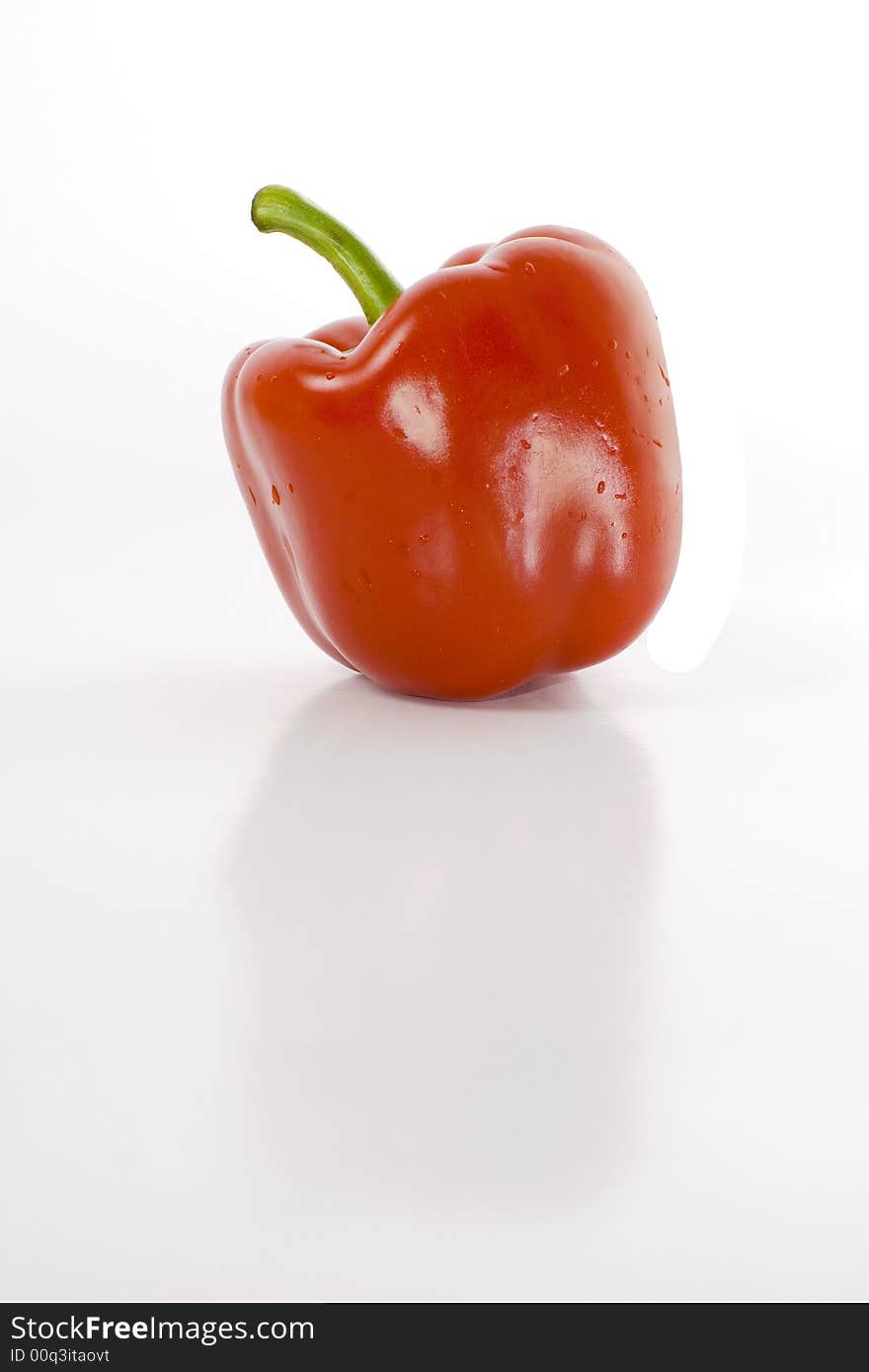 Sweet red pepper isolated on white with reflection on glossy surface.