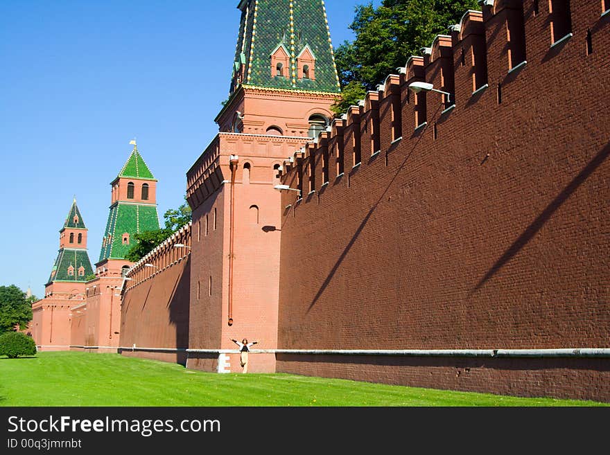 Old Russian outstanding memorial - fortified wall with towers from red brick, detail of Kremlin fortress in Moscow. And small figure of woman. Old Russian outstanding memorial - fortified wall with towers from red brick, detail of Kremlin fortress in Moscow. And small figure of woman.