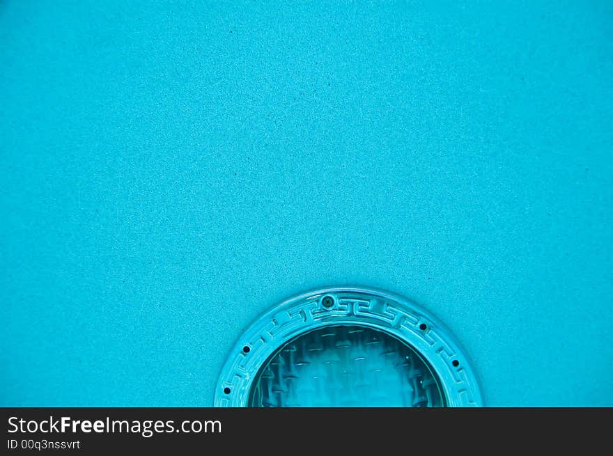 Horizontal view of top half of underwater pool light in clear blue water