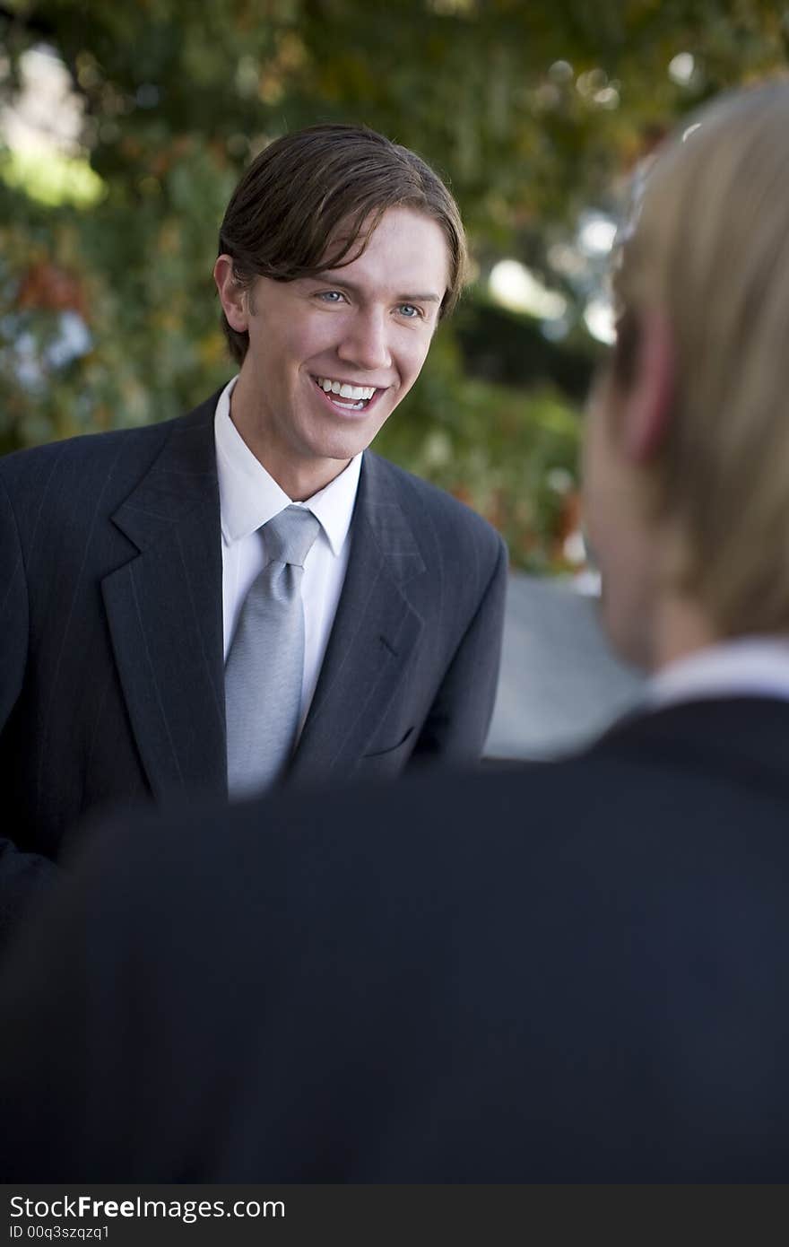 Over shoulder view of businessman standing in suit and tie talking. Over shoulder view of businessman standing in suit and tie talking