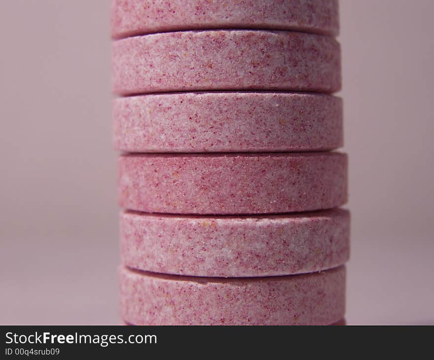 Stack of pink and purple multivitamins, isolated on dark pink background, closeup macro. Stack of pink and purple multivitamins, isolated on dark pink background, closeup macro