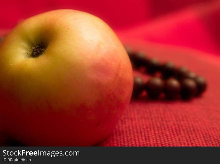 Single apple macro close up red background prayer beads. Single apple macro close up red background prayer beads