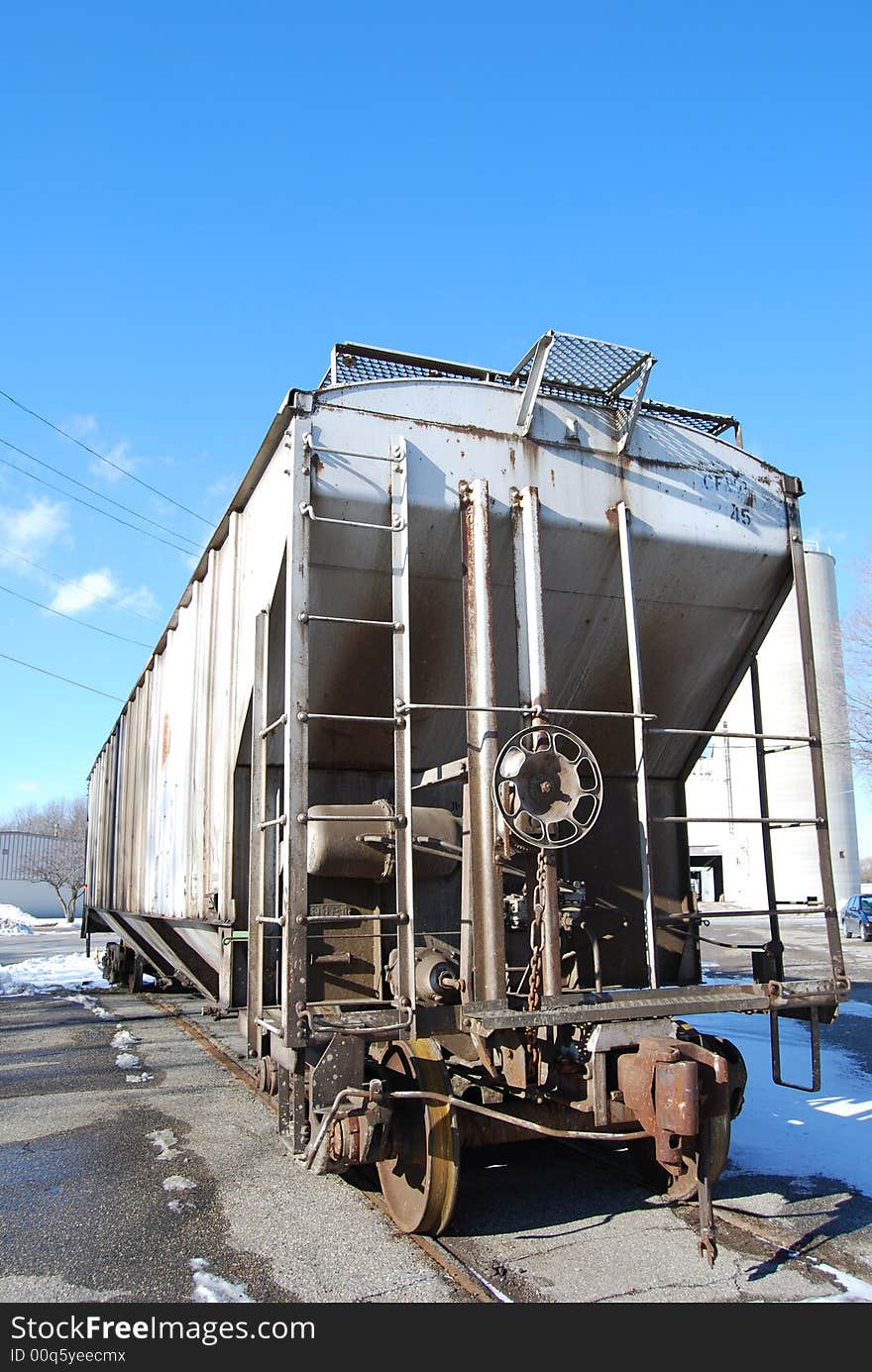 A train car parked on a siding on a bright blue sunny, but cold winter day.