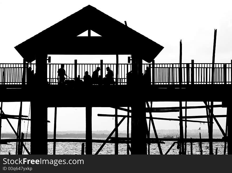 A silhouette outline of a shelter built along the shoreline. A silhouette outline of a shelter built along the shoreline