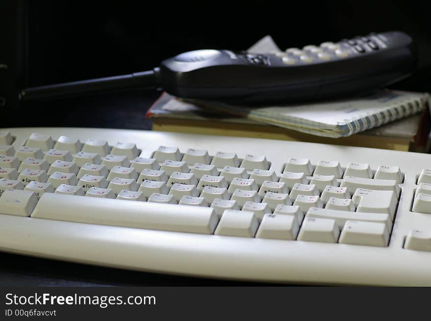 Keyboard, telephone and notebook, by closeup, against the black background. Keyboard, telephone and notebook, by closeup, against the black background.