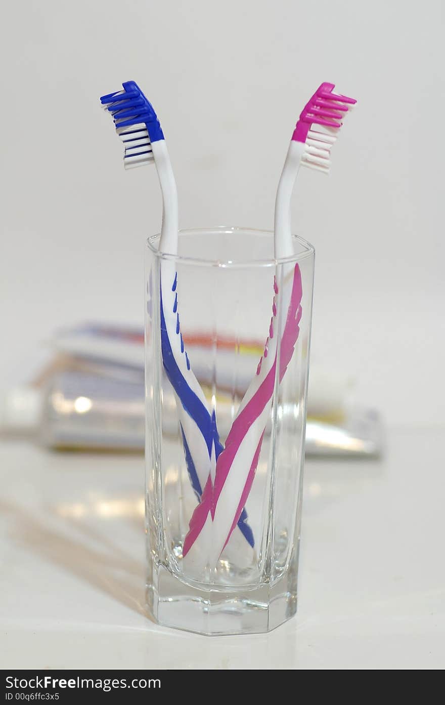 Two toothbrushes in the glass container against the bright background. Two toothbrushes in the glass container against the bright background.