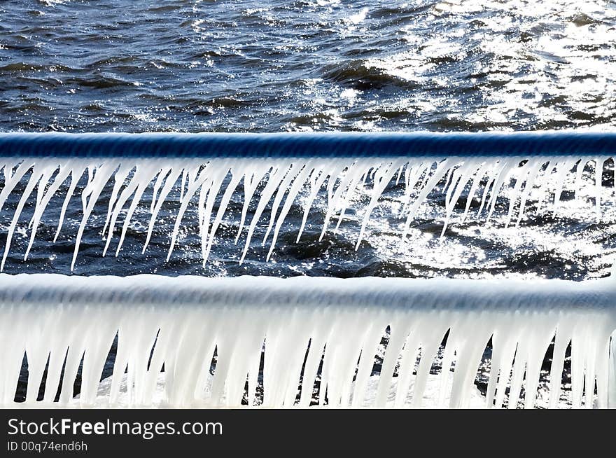 Spray from the cold January water form icicles on the railings of the Holland Harbor channel back lit from an afternoon sun. Spray from the cold January water form icicles on the railings of the Holland Harbor channel back lit from an afternoon sun