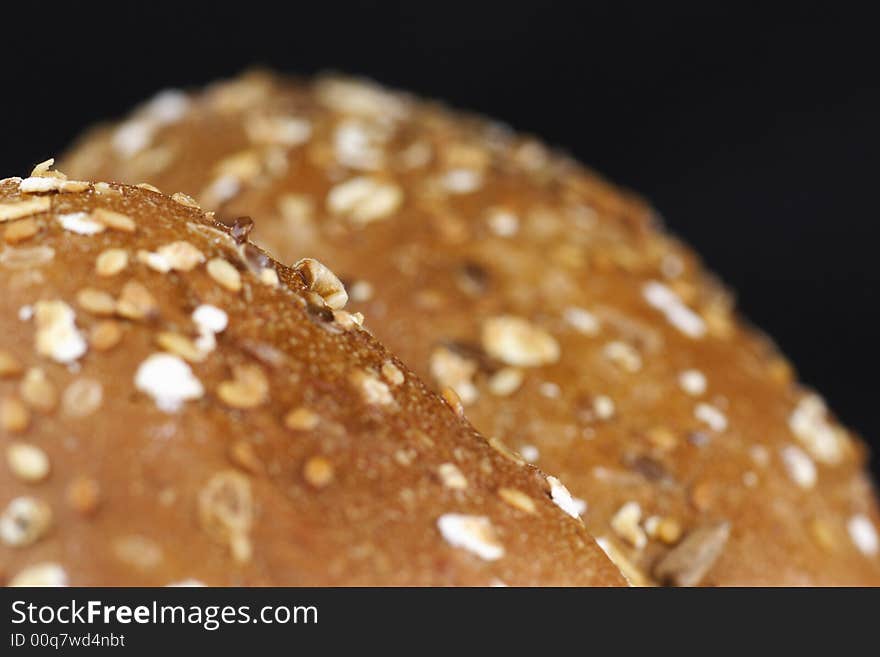 Close-up photo of roll bakery with cereal at black background. Good Appetite!