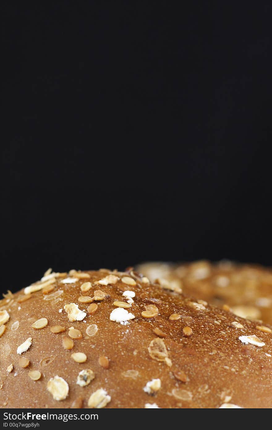 Close-up photo of roll bakery with cereal at black background. Good Appetite!