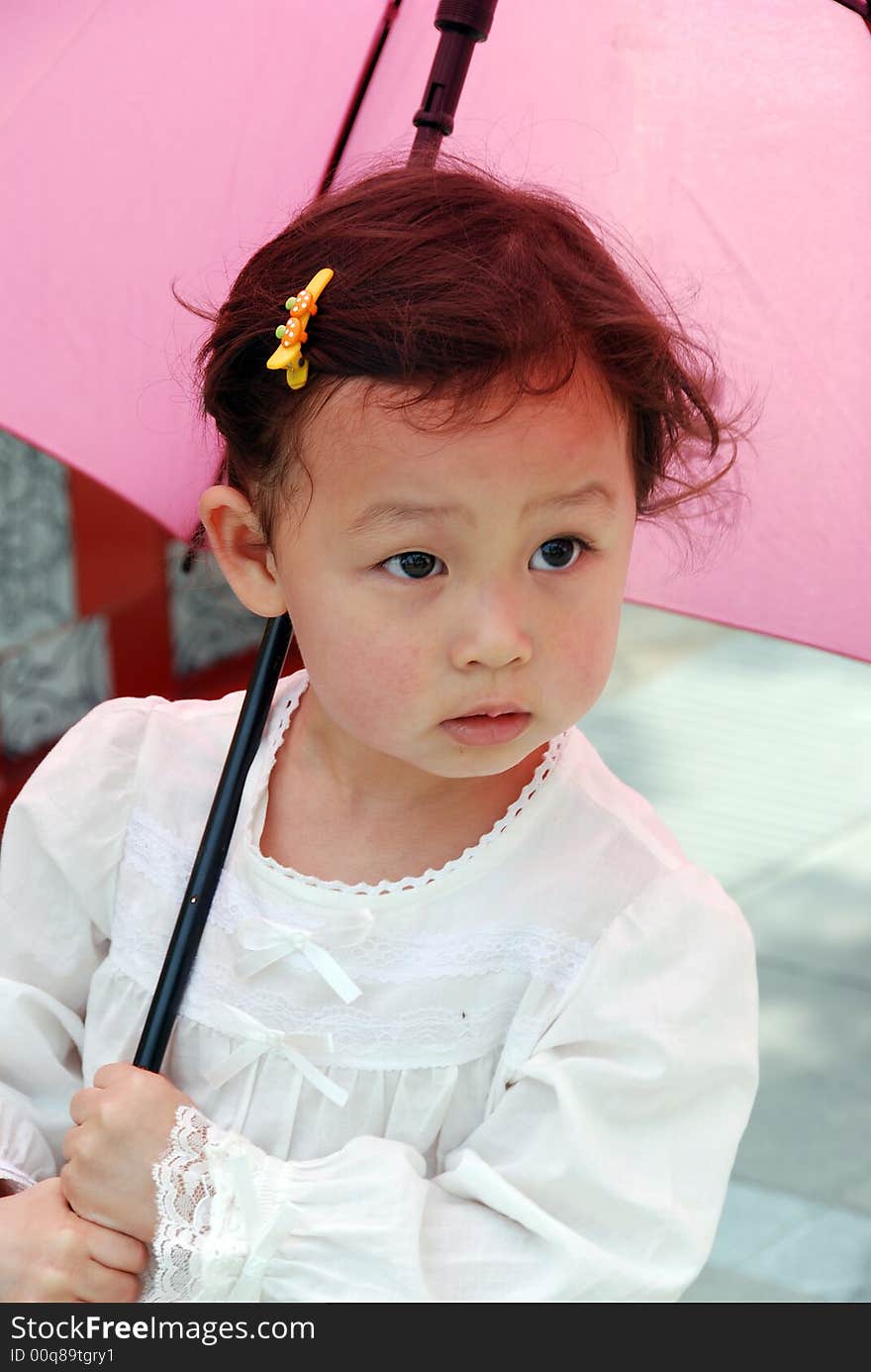 Cute beautiful Chinese young child under umbrella in summer