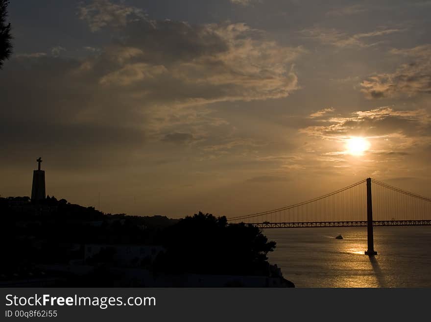 Bridge 25 de Abril over Tagus river and Cristo Rei in Lisbon/Almada at sunset. Bridge 25 de Abril over Tagus river and Cristo Rei in Lisbon/Almada at sunset