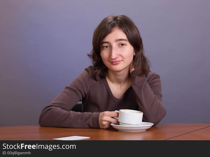 The beautiful girl with a coffee mug on a grey background. The beautiful girl with a coffee mug on a grey background