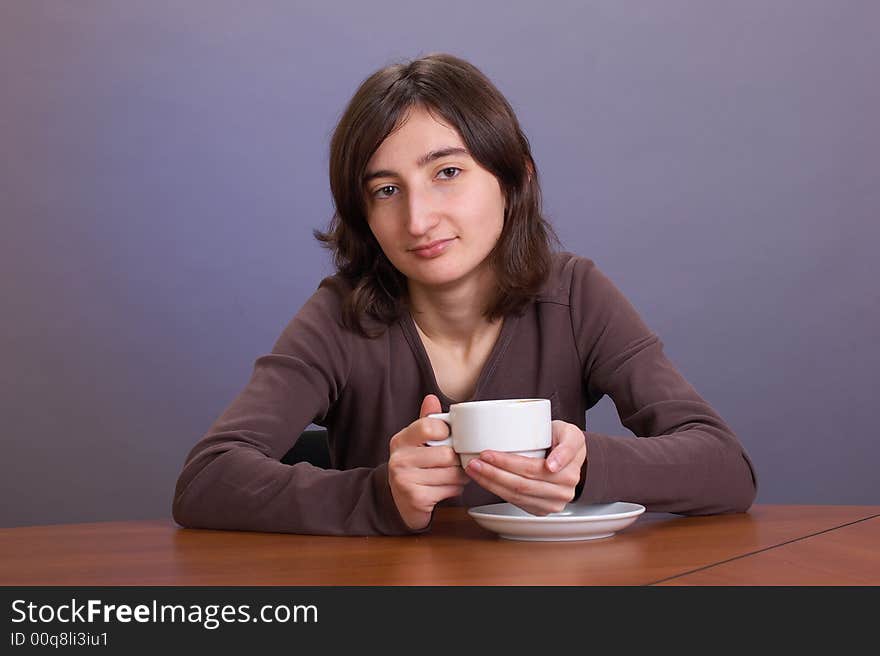 The beautiful girl with a coffee mug on a grey background. The beautiful girl with a coffee mug on a grey background