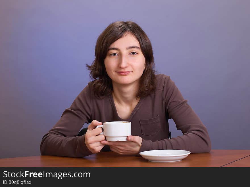 The beautiful girl with a coffee mug on a grey background. The beautiful girl with a coffee mug on a grey background