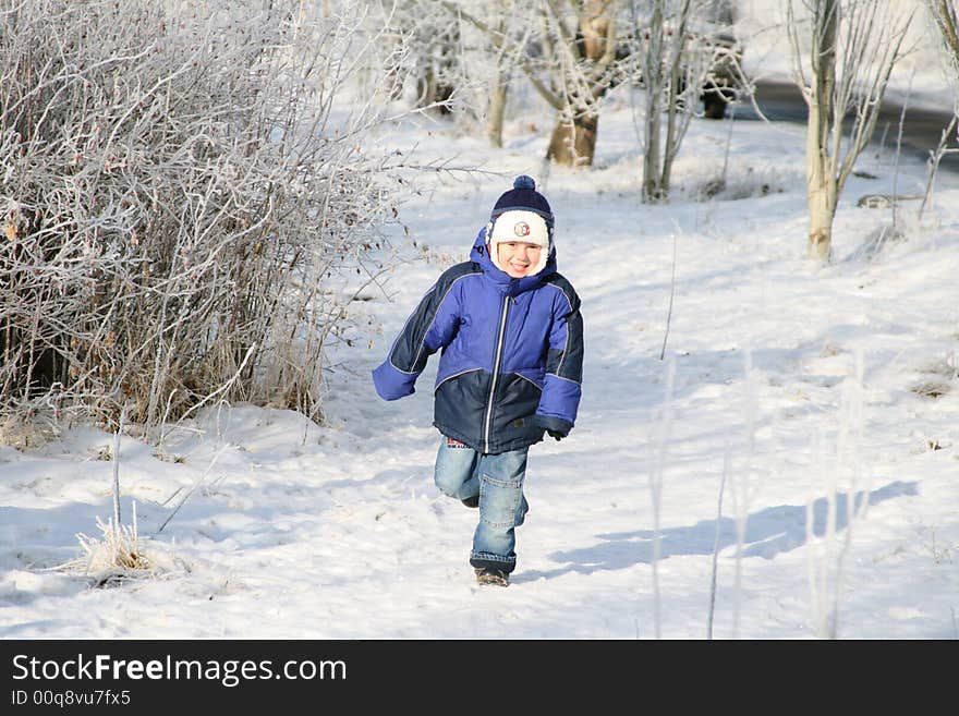 The boy runs in the winter on a footpath in park. The boy runs in the winter on a footpath in park