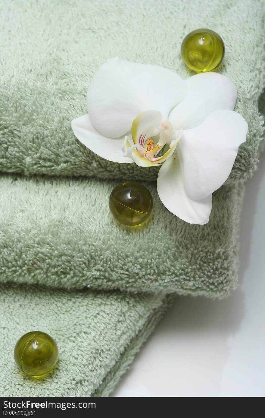 Bath oil pearls with orchid and green towels. Bath oil pearls with orchid and green towels.