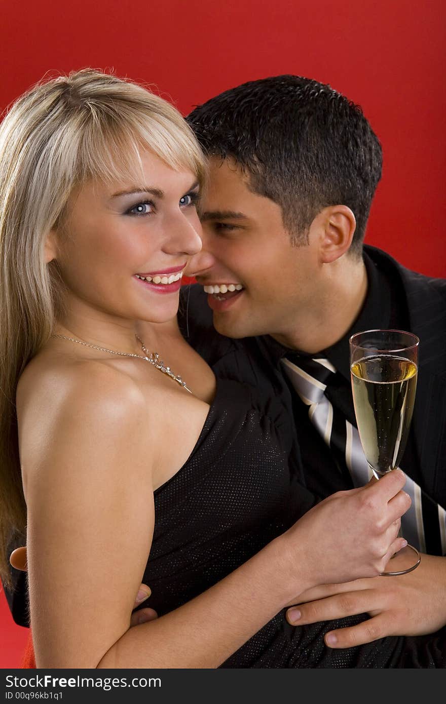 Young, hugging and smiling couple. Woman is holding glass of champagne. Young, hugging and smiling couple. Woman is holding glass of champagne